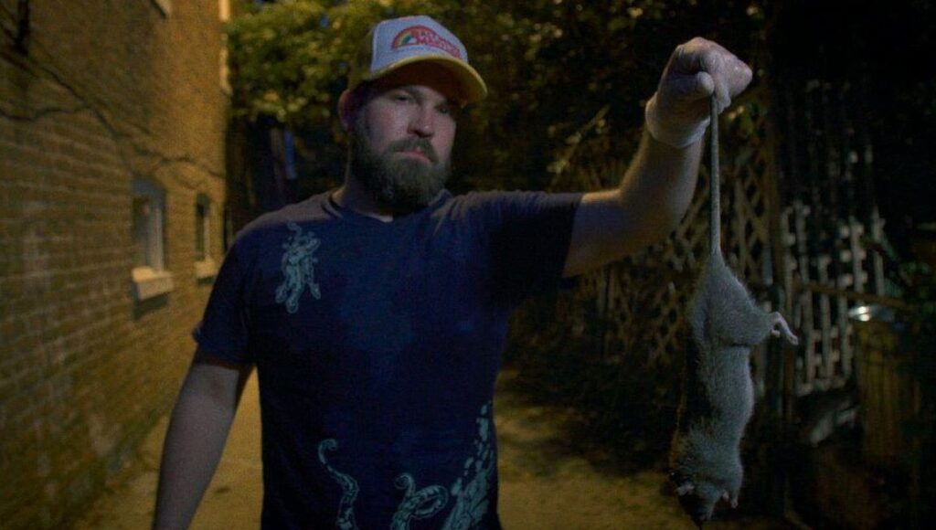 Rat Film | Theo Anthony Rat Film: Man holds rat by tail. Baltimore documentary film about rats, history, and urban ecology.