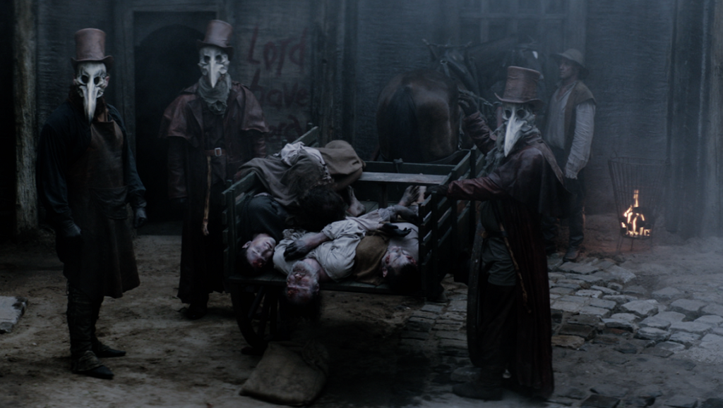 The Reckoning movie scene: Plague doctors surround a cart of bodies. Fantasia Fest 2020 horror film.