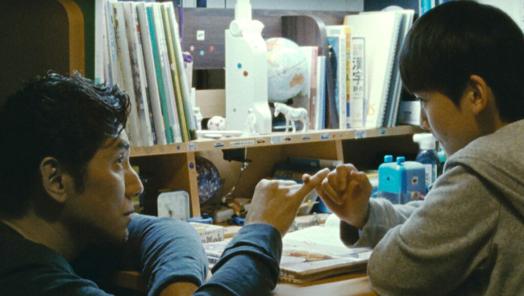 The Long Excuse movie scene. Man and boy pinky swear at a desk. Miwa Nishikawa film.
