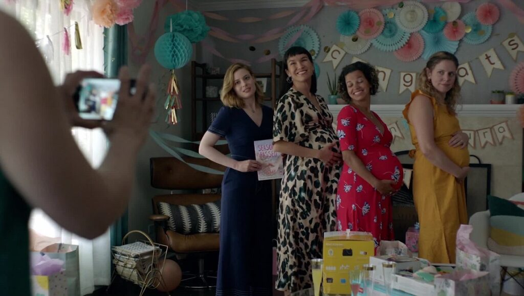 I Used to Go Here film still: Women at a baby shower. Pregnant women pose for a photo. Party decorations.