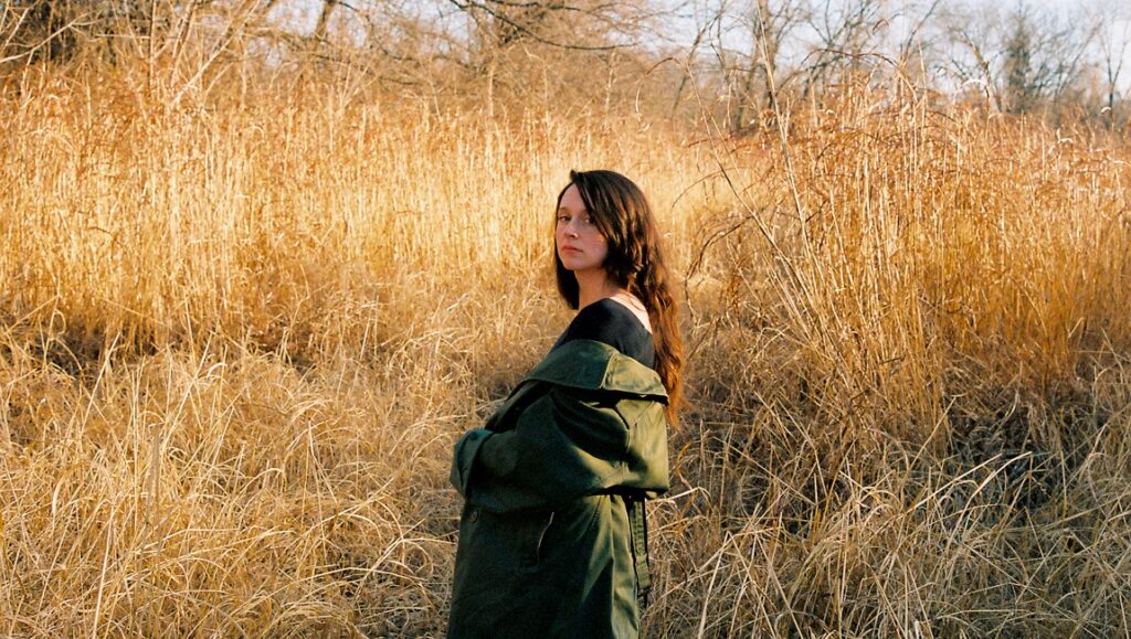 Waxahatchee | Saint Cloud Waxahatchee Saint Cloud album art. Katie Crutchfield in a field of tall grass, wearing a green coat. Indie rock.