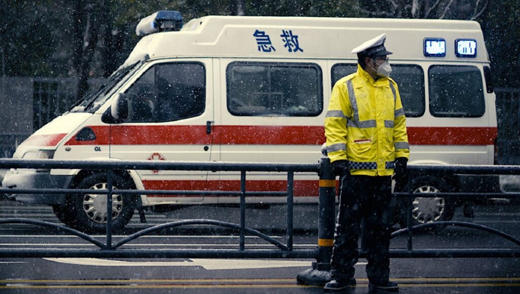 76 Days film image: Paramedic in mask stands near ambulance in the snow. Hao Wu & Weixi Chen directed the documentary.