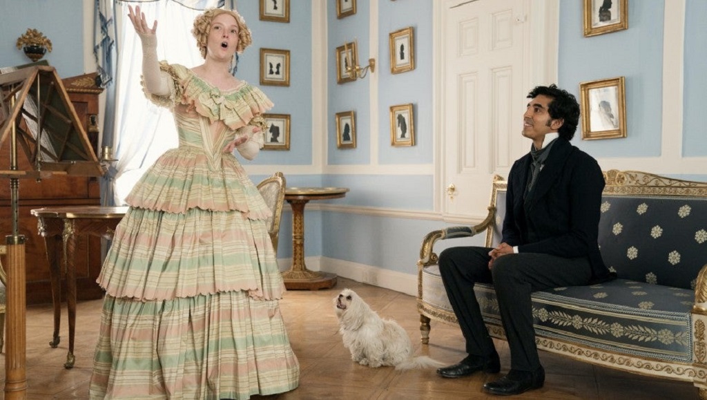 The Personal History of David Copperfield film scene. Woman in period dress sings to seated man. Dog sits nearby.