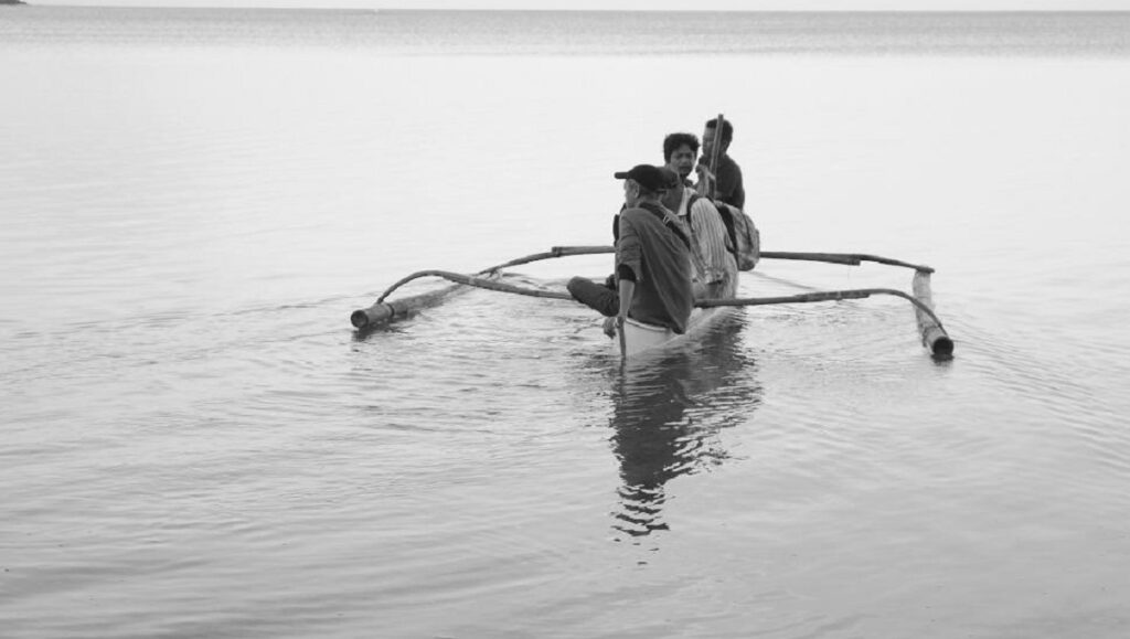 Black and white still from Lahi, Hayop at Venice Film Festival. People in a small boat on the water.