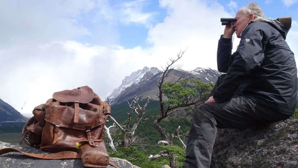 Werner Herzog, Nomad. Man with binoculars, leather backpack, mountain view. Nomad: In the Footsteps of Bruce Chatwin.