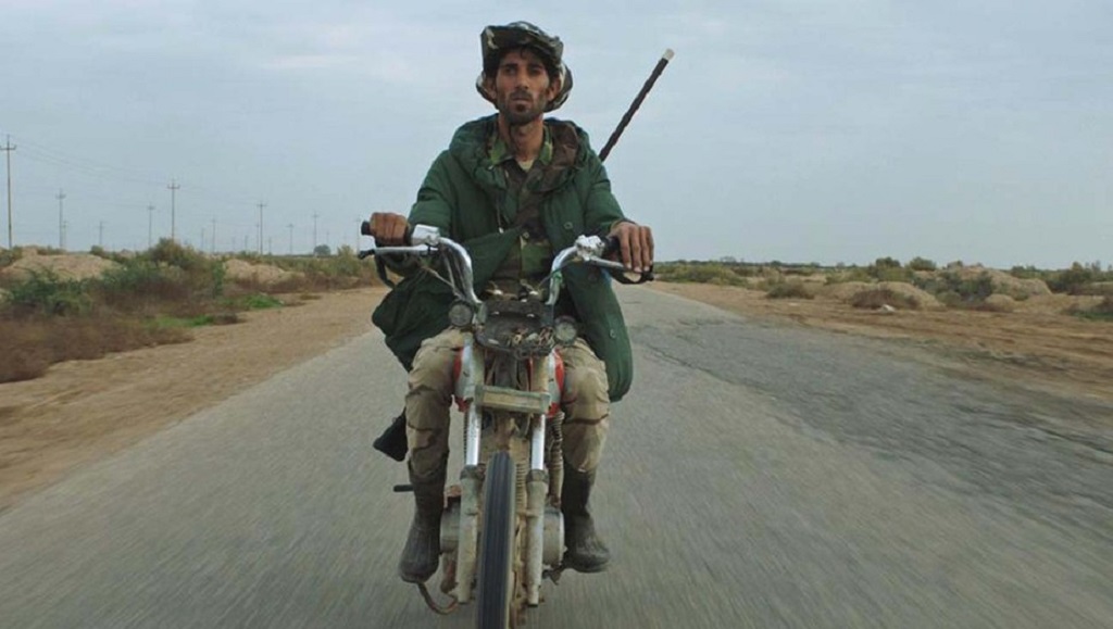 Notturno film still: A man rides a motorcycle on a desolate road, embodying the film's themes of night and conflict.