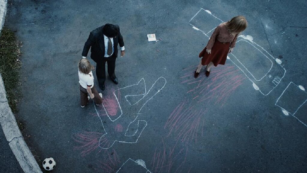 Padrenostro | Claudio Noce Padrenostro film still. Family stands near chalk outlines on asphalt. Claudio Noce movie scene.