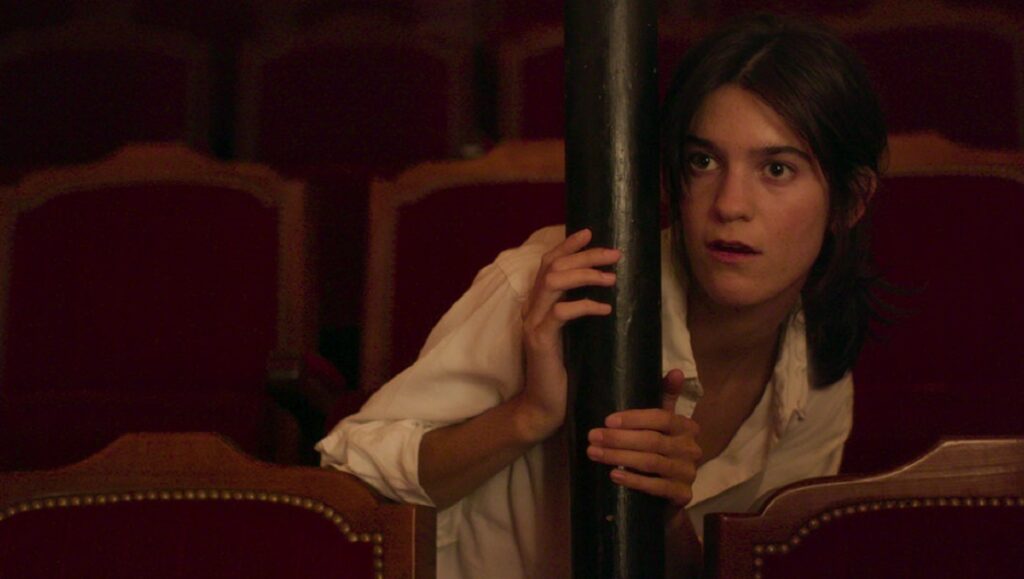 Spring Blossom | Suzanne Lindon TIFF 2020: Spring Blossom film still. Young woman in theater, looking surprised. Film festival coverage.