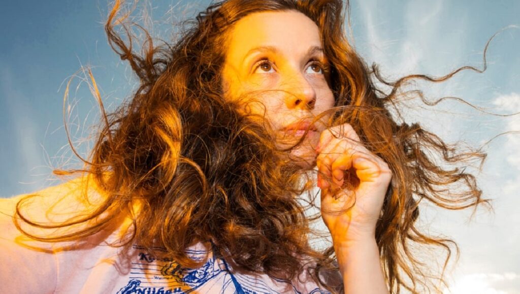 Jessy Lanza portrait. Musician with curly hair, looking up at a blue sky. Pop Rocks Q3 2020 music issue.