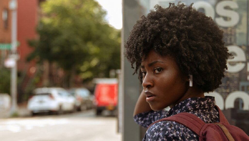 Farwell Amor | Ekwa Msangi Ekwa Msangi's Farewell Amor: Woman with Afro, backpack, looking back on a city street. Indie film still.