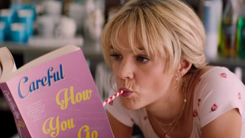 Promising Young Woman | Emerald Fennell Carey Mulligan in Promising Young Woman reads a book with a straw in her mouth. Emerald Fennell film.