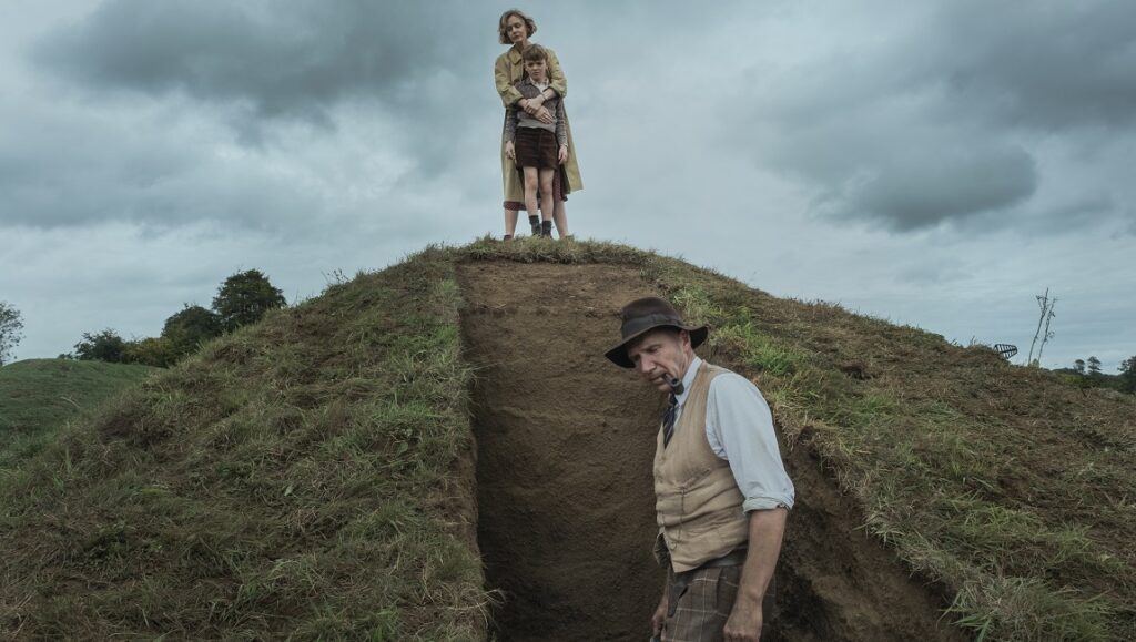 The Dig movie scene: Carey Mulligan, Ralph Fiennes, and young boy on excavation site.