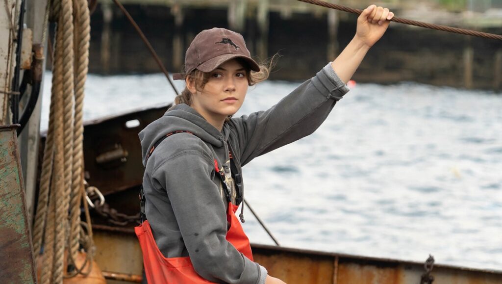 Sundance Film Festival 2021 — Dispatch 1: CODA, Human Factors, The Pink Cloud Still from CODA at Sundance Film Festival. Emilia Jones on a fishing boat, wearing a cap and orange bib overalls.