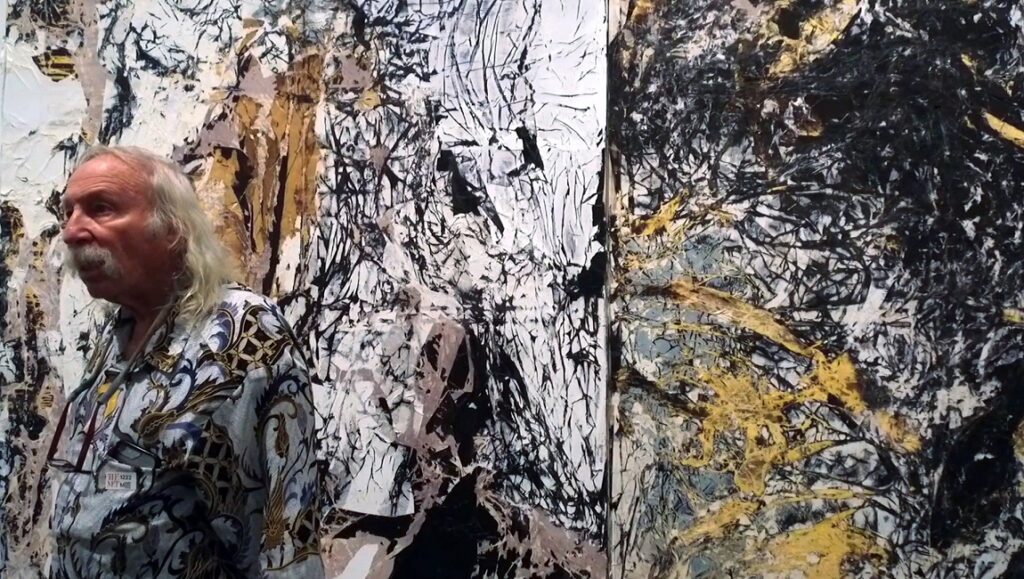 Film About a Father Who | Lynne Sachs Still from Film About a Father Who by Lynne Sachs. Man with mustache stands by abstract art.