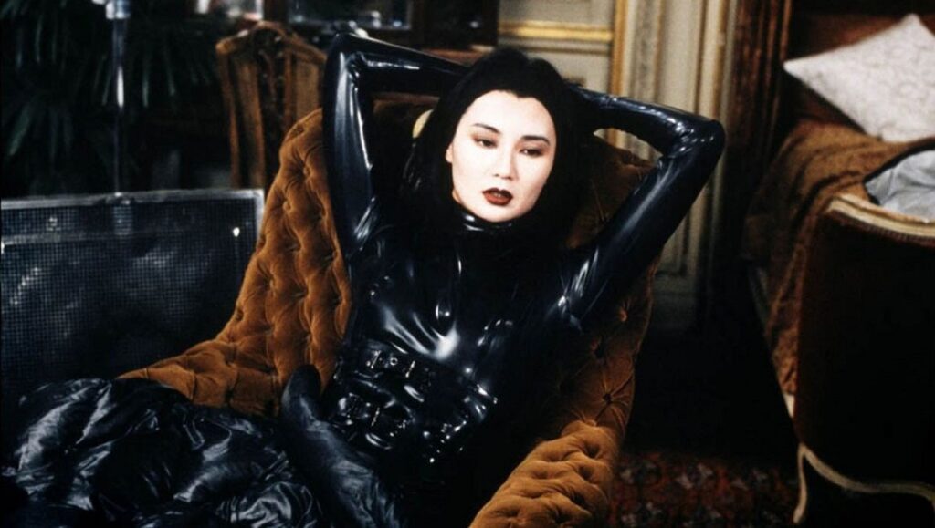 Irma Vep | Olivier Assayas Maggie Cheung as Irma Vep, Olivier Assayas film. Actress in black latex catsuit reclining in chair.