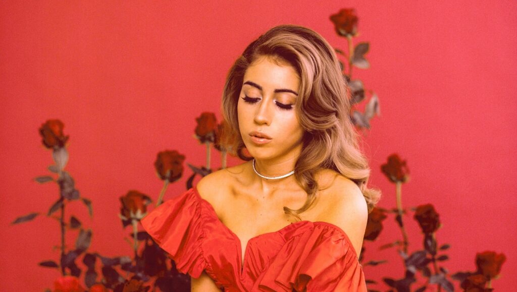Kali Uchis Sin Miedo album art. Singer in red dress with roses, against a red background.