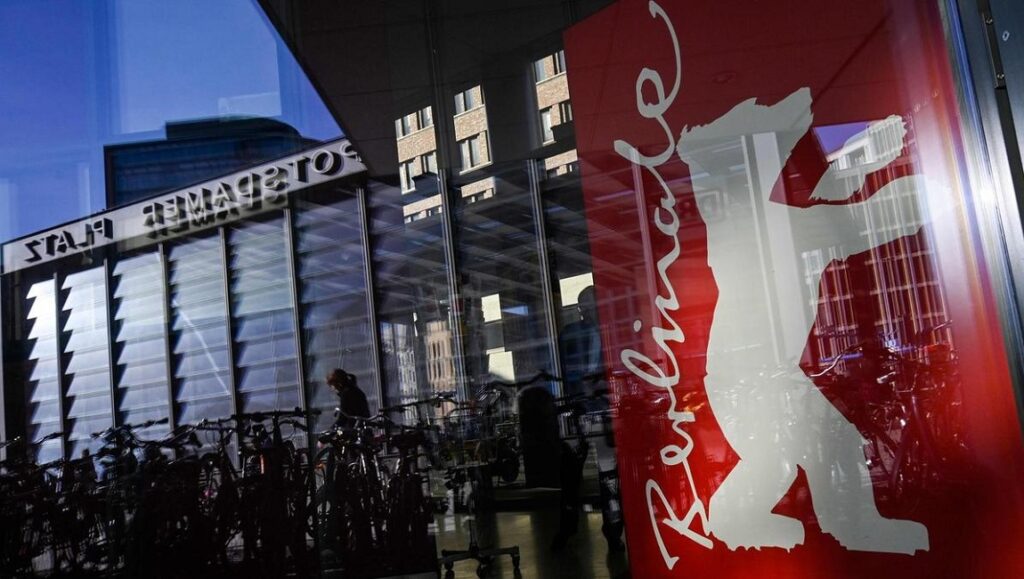 Berlin Film Festival (Berlinale) sign with bear logo. Reflections of buildings and bikes.