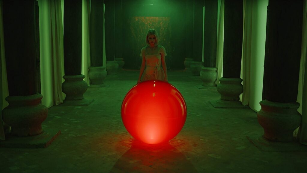 Still from Blazing World at Sundance Film Festival. Woman with red orb in a green room with pillars.