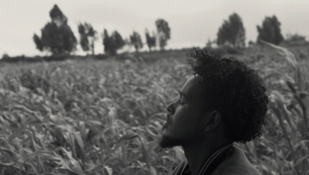 Faya Dayi | Jessica Beshir Black and white still from Life in a Day 2020 at Sundance Film Festival. Man in field looks up.