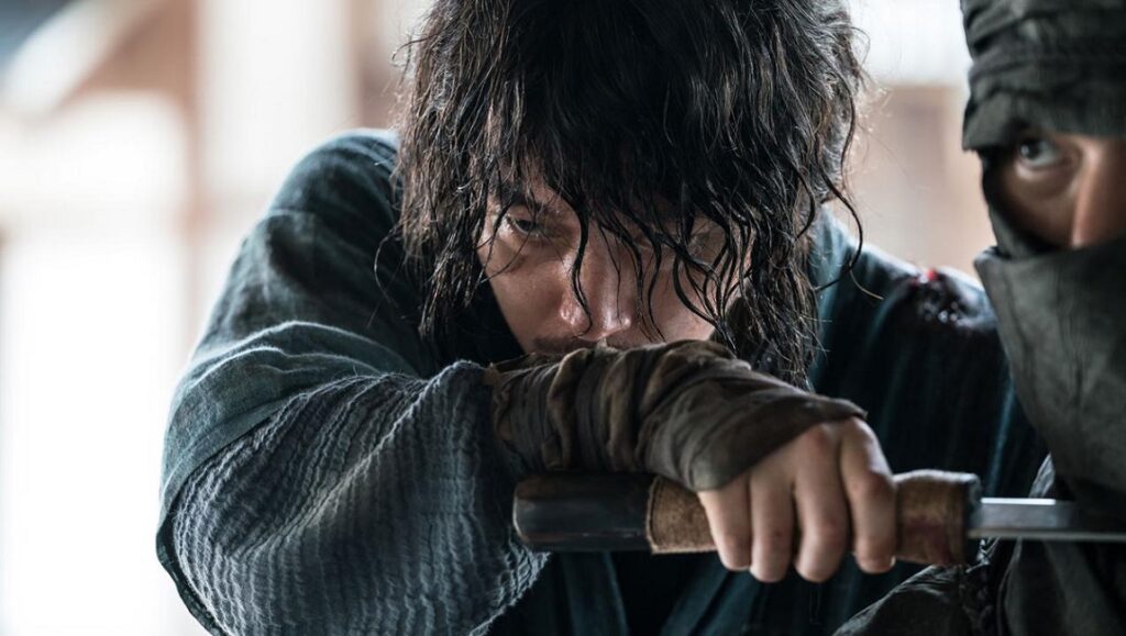 Choi Jae-hoon's The Swordsman: A warrior grips his sword, intense gaze. Action film, martial arts.