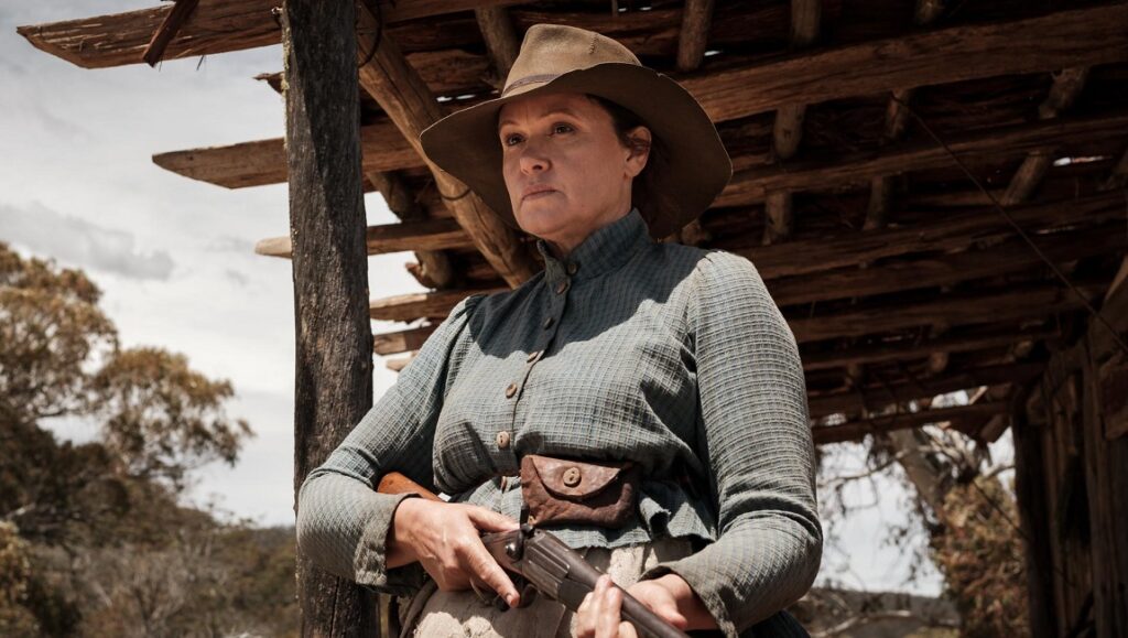 The Drover’s Wife — Leah Purcell The Drover's Wife film still from SXSW 2021. Woman with rifle and hat.