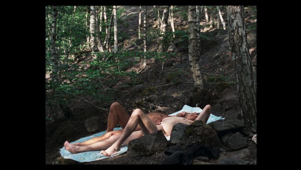 Two nude men lying on a blanket in the woods, as seen at the Berlin Film Festival 2021.