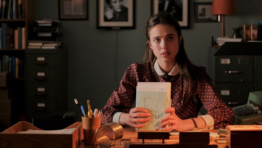 Margaret Qualley as Joanna Rakoff in My Salinger Year movie scene. Woman at desk with papers, typewriter.