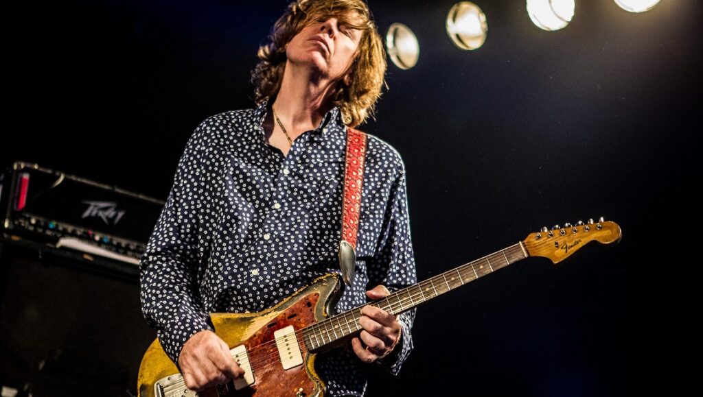 Thurston Moore performing live. Guitarist playing electric guitar on stage. Screen Time.