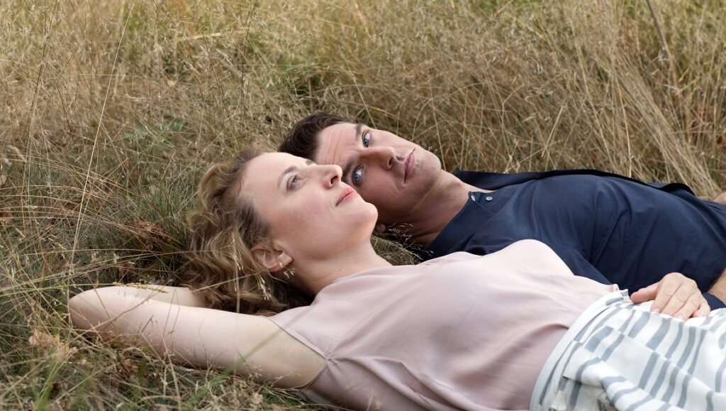 I’m Your Man | Maria Schrader I'm Your Man movie still. Alma and Tom lie in the grass, gazing upwards. Romantic comedy film.