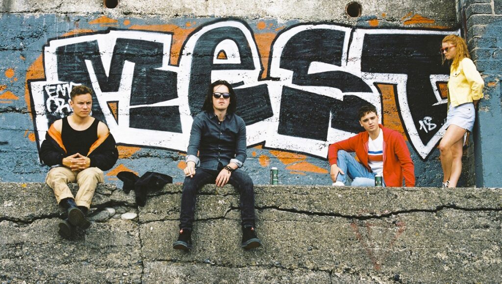 Here Are the Young Men | Eoin Macken Here Are the Young Men cast: Anya Taylor-Joy, Dean-Charles Chapman, and others pose against graffiti.