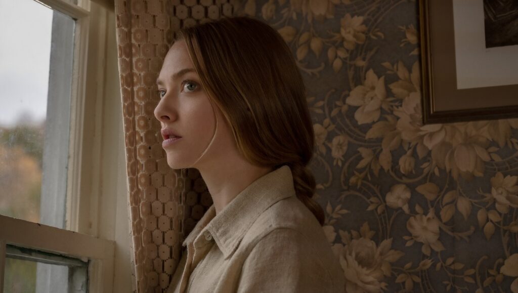 Things Heard and Seen | Shari Springer Berman & Robert Pulcini Amanda Seyfried in Things Heard and Seen looks out a window. Floral wallpaper backdrop. Shari Springer Berman & Robert Pulcini film.