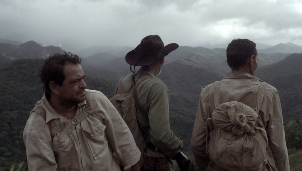 Neighboring Scenes 2021: Between Dog and Wolf, All the Dead Ones, Samichay Between Dog and Wolf film still. Three men with backpacks overlook a mountainous landscape. Neighboring Scenes 2021.
