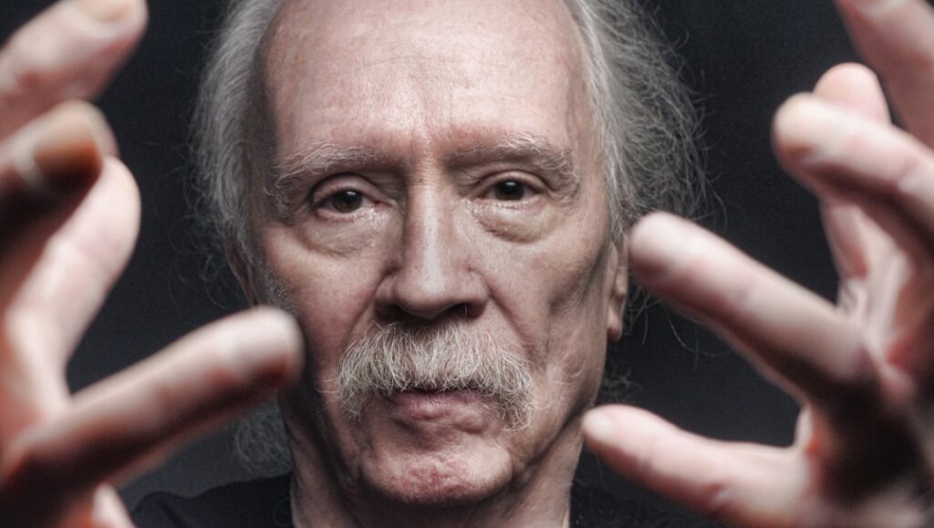 Movies Don’t Scare Me: A Decade of John Carpenter Close-up of John Carpenter, horror movie director, with hands outstretched.