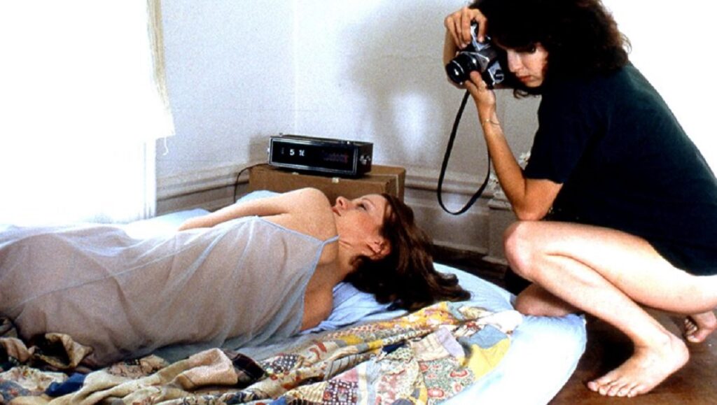 Girlfriends | Claudia Weill Still from Claudia Weill's Girlfriends film. Woman with camera photographs a friend lying on a bed.