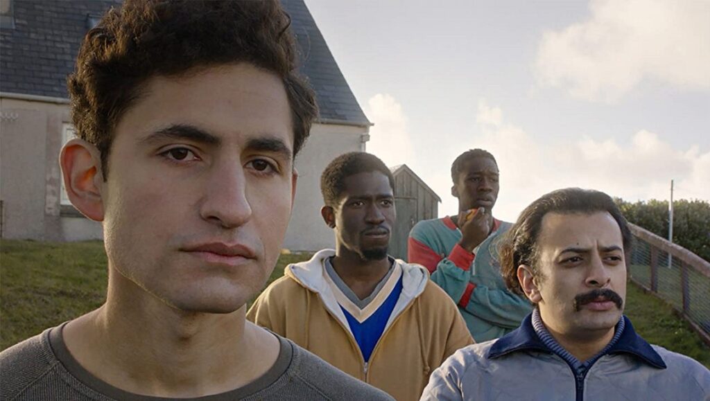 Limbo | Ben Sharrock Limbo film still: Four men stand outdoors. Ben Sharrock film about refugees.