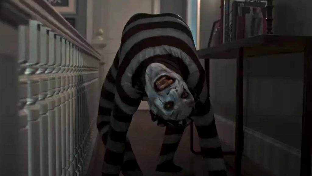 Separation movie scene: Creepy clown figure in striped suit lurking in hallway. Horror film imagery.