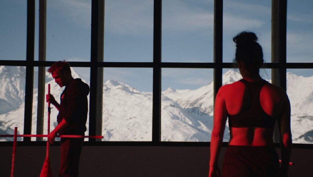 Slalom film still: Skiers in training with snowy mountain backdrop.