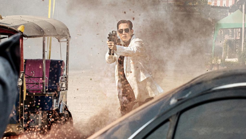 Deliver Us from Evil | Hong Won-chan Deliver Us from Evil Korean action film scene. Man in white suit aims gun amidst chaos, tuk-tuk, and car nearby.