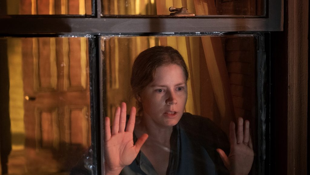 Woman in the Window | Joe Wright Amy Adams in Woman in the Window movie. Actress with hands on glass, looking worried. Joe Wright film.