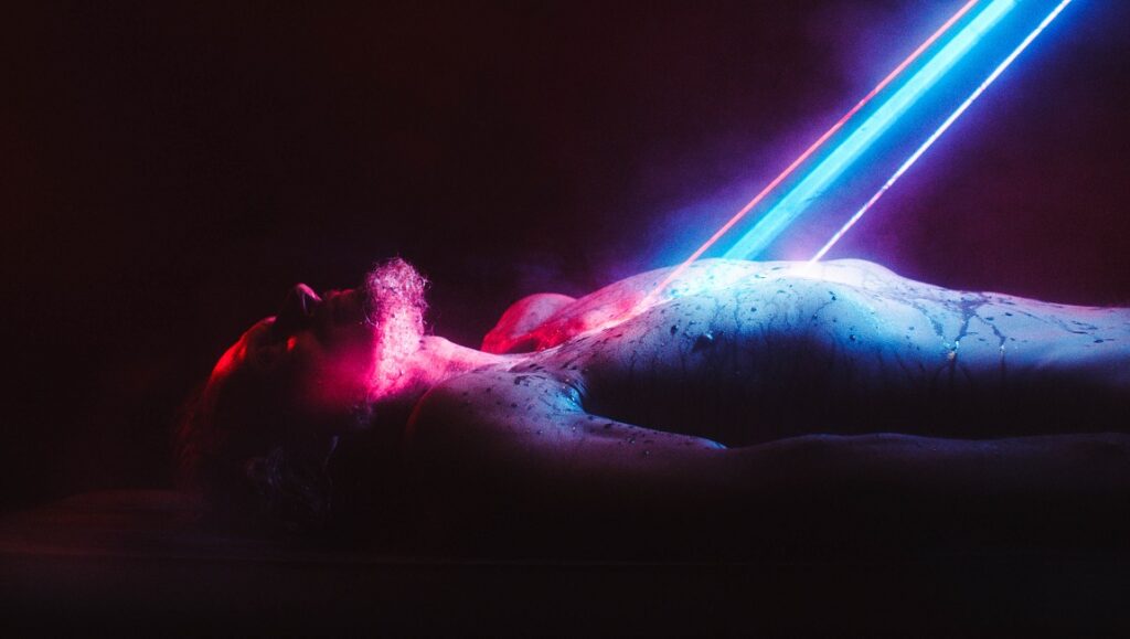 Fried Barry | Ryan Kruger Still from Fried Barry by Ryan Kruger. Body illuminated by neon lights. Sci-fi horror film.