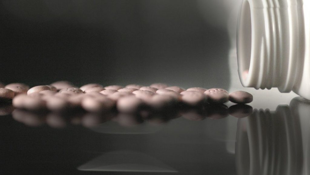 Pills spilling from a bottle. Opioid crisis, pain medication, The Crime of the Century.