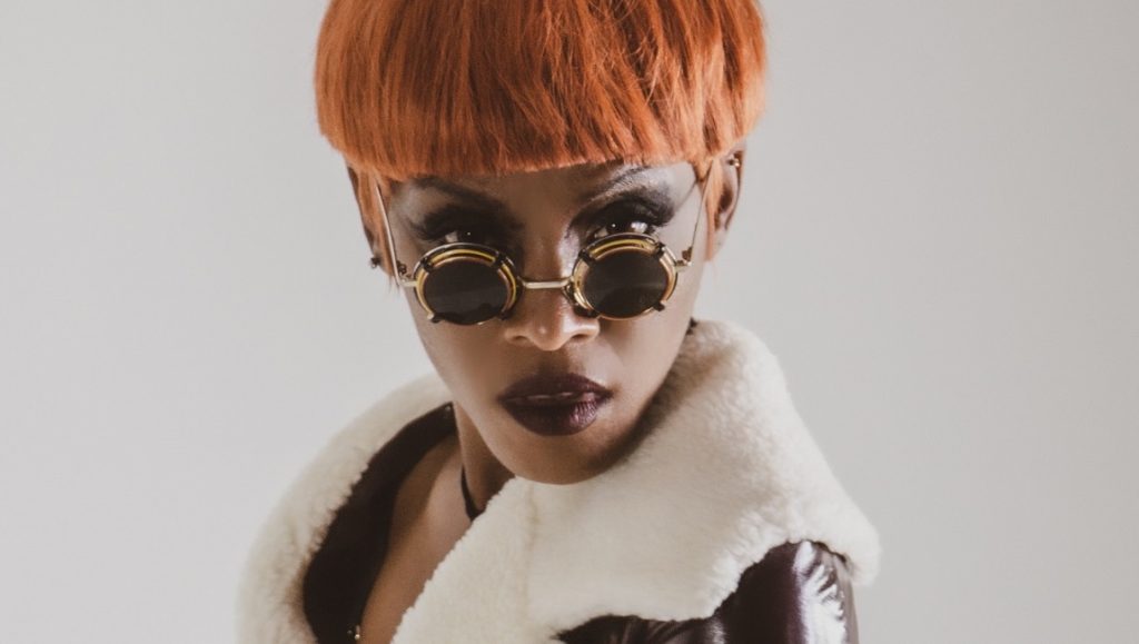 Dawn Richard | Second Line: An Electro Revival Dawn Richard album art. Singer with orange hair, round sunglasses, and a white fur-lined coat. April 2021 music.