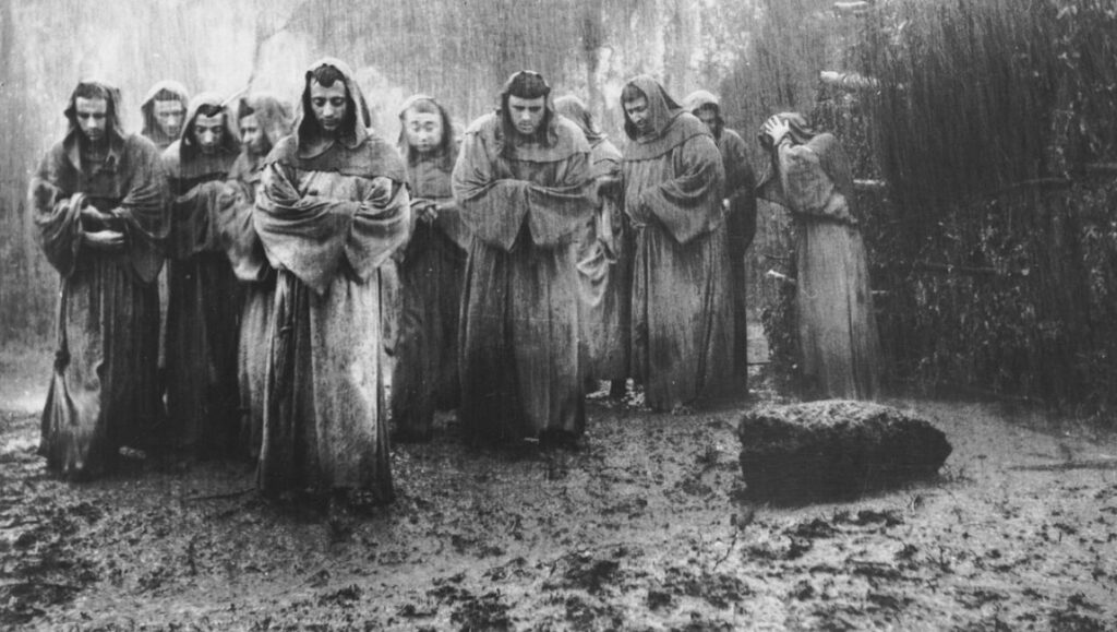 The Flowers of St. Francis film still. Monks in robes stand in the rain. Roberto Rossellini film.