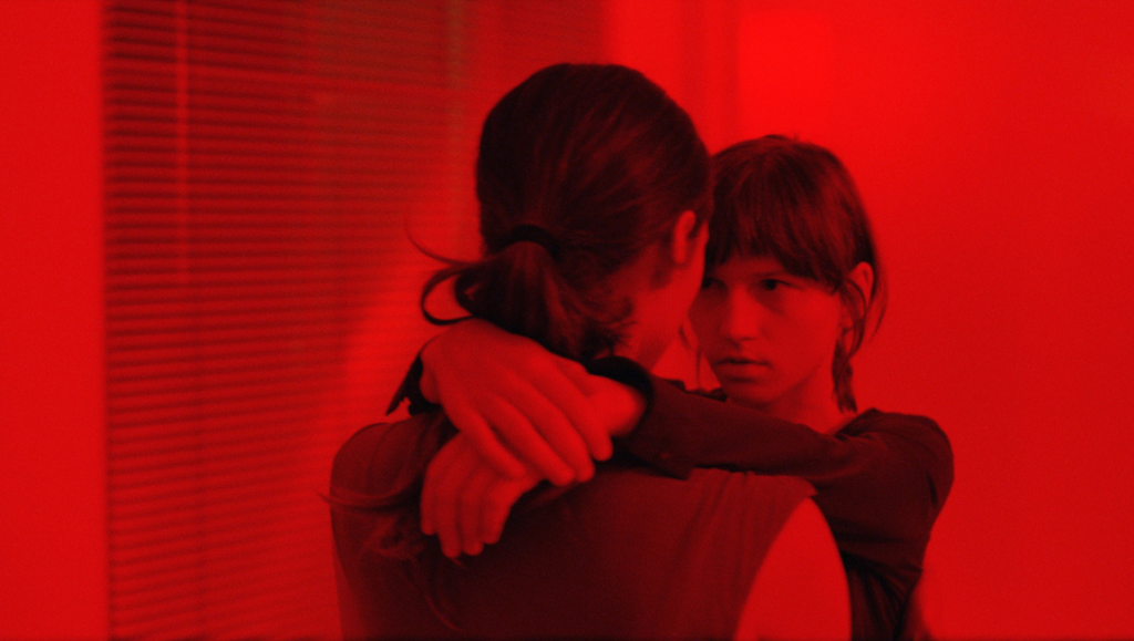Two girls hugging in red light. Friendship, love.