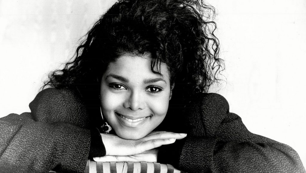 Janet Jackson Control era, black and white portrait. Curly hair, smiling.