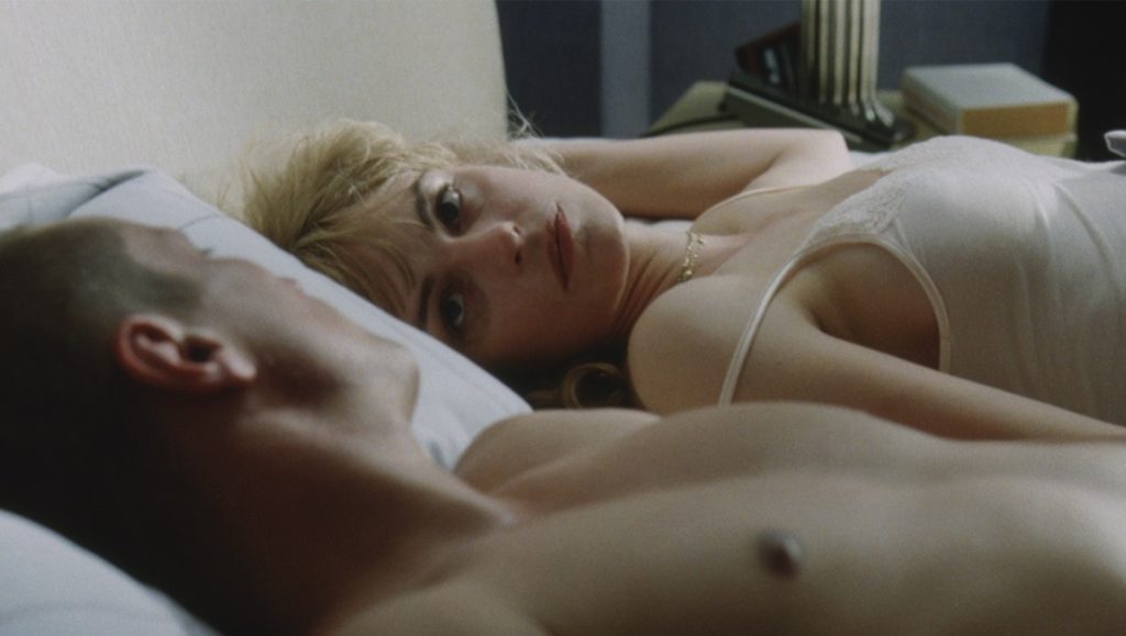 Jerichow | Christian Petzold Scene from Jerichow movie: Woman in lingerie looks at man in bed. Intimate moment, drama, love.
