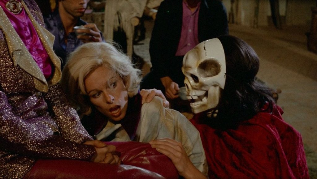 Scene from Jacques Rivette's Noroît: Woman with skull mask, blonde woman, and other characters.