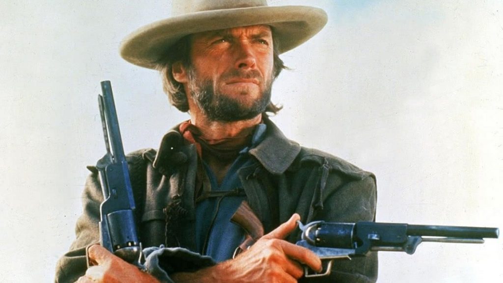 Clint Eastwood as Josey Wales. Western film gunslinger with revolvers and cowboy hat.