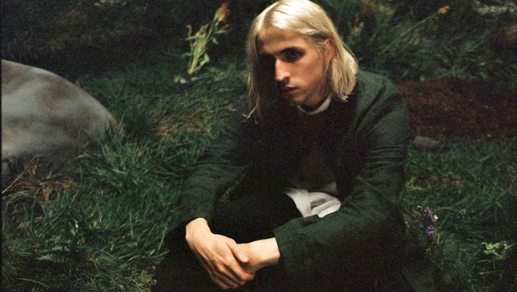 Best Albums of 2021: Porter Robinson | Nurture Porter Robinson sits in a field. Featured in April 2021 album roundup.