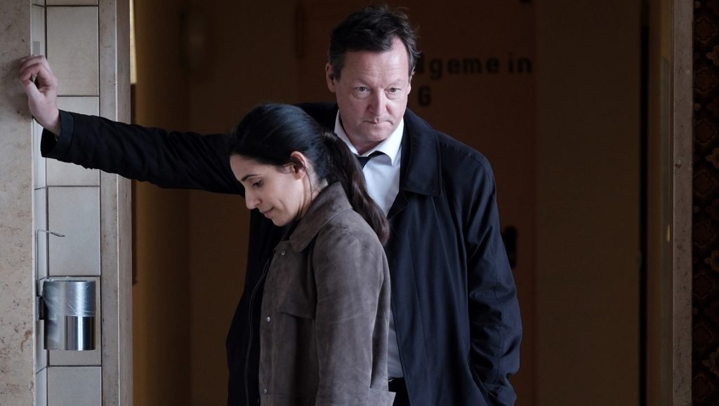 Tatort scene: Two detectives, a man and a woman, investigate a crime scene. German TV crime drama.